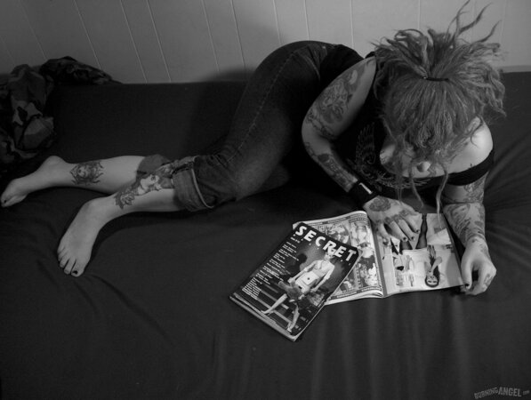 Chick with fuzzy hair reads a magazine and masturbates in black and white