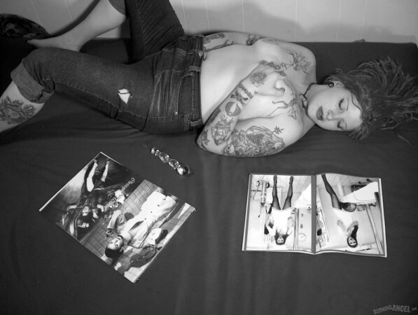 Chick with fuzzy hair reads a magazine and masturbates in black and white