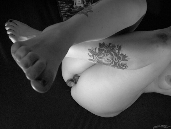 Chick with fuzzy hair reads a magazine and masturbates in black and white