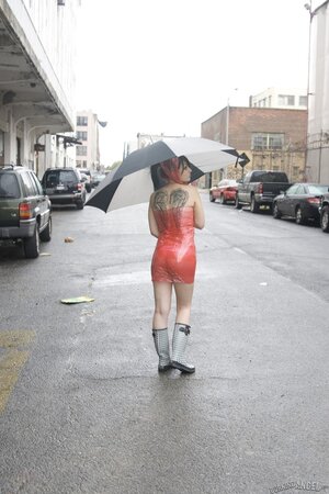 Concupiscent student in red plastic goes under a bridge to flash tattooed wings