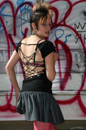 Sexy punk woman with a mohawk pulls her pink pantyhose down to show the vagina