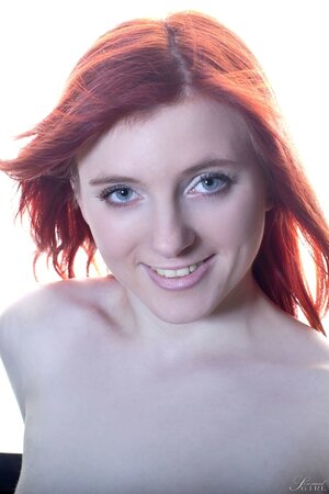 Fragile minx with red hair demonstrates her pale-skinned body on the table