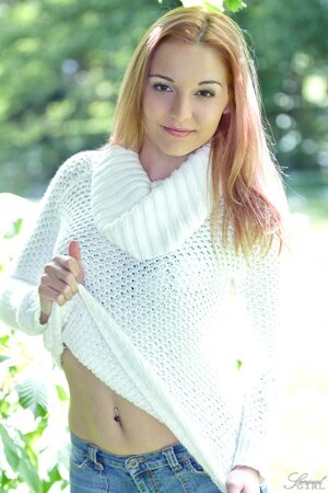 Cute young babe posing nude in the field and showing her shaved pussy