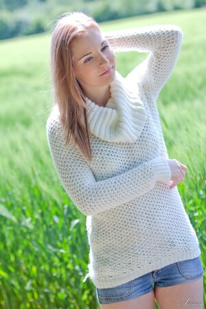 Cute young babe posing nude in the field and showing her shaved pussy