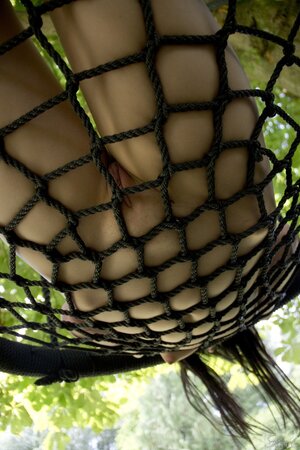 Seductive tender brunette undressing to show her awesome pussy on a swing