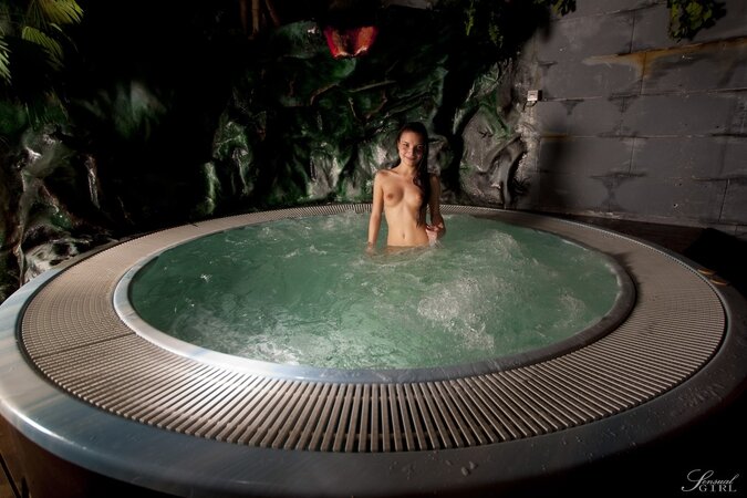 Instead of sleeping petite brunette visits an outdoor jacuzzi in the nighttime