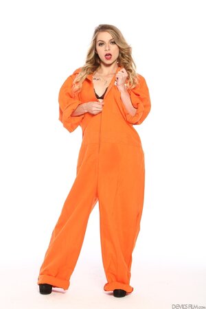 Female inmate in orange uniform flashes pierced nipple to seduce prison guard