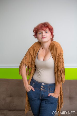 Amateur redhead model spreads legs to reveal her pink shaved pussy on the couch