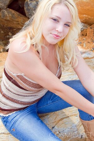 Blonde fatty removes her top to demonstrate a pair of perky breasts on the rocks