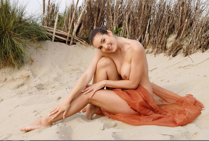 Playful brunette with sexy bush poses on the beach with only piece of cloth
