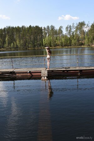 Sexy whore deletes flower dress on the pier and goes posing naked in the puddle