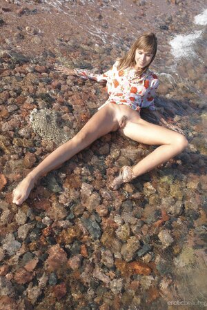 Naked young hussy gets into various positions to show her pussy in the ocean