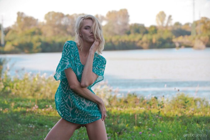 Excited slim blonde poses showing her small boobs and trimmed cunt on the meadow
