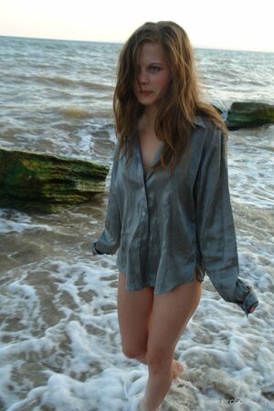 Young sexy cutie gets wet and naked when posing playfully in the sea