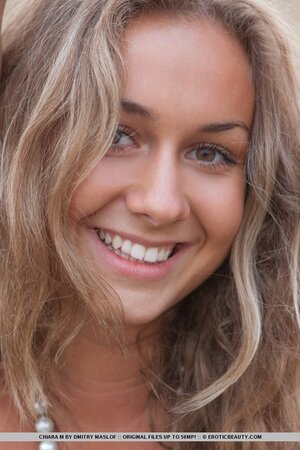 Attractive young doll smiles while showing off her naked body in the field