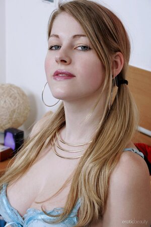 Smiling young woman with two ponytails removes blue bra and panties in bed