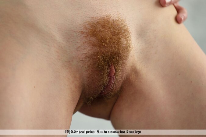 Cute witch with red hair poses naked and shows off her delicious bush