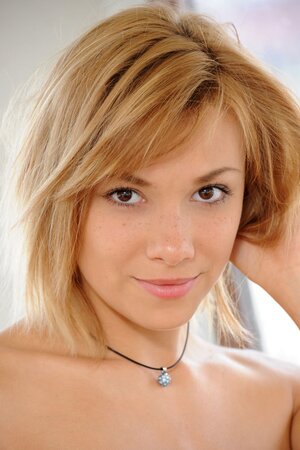 Blond girl with round natural boobs poses completely naked on a boat