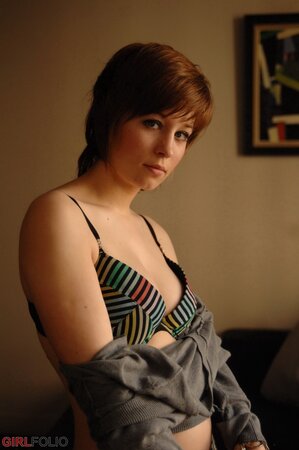 Playful short-haired lassie pulls off sweater to erotically pose in undies