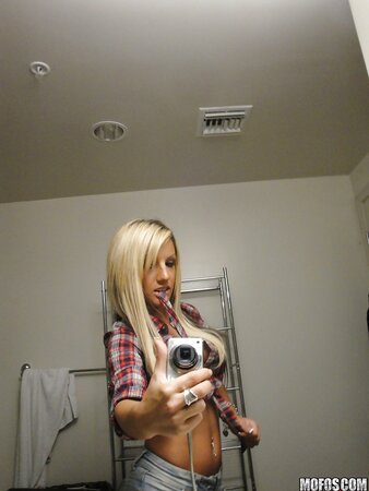 Slim young woman enjoys taking selfie in the bathroom being completely naked