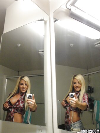 Slim young woman enjoys taking selfie in the bathroom being completely naked