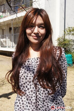 Eastern redhead in a shirt poses for photographer against a apartment building