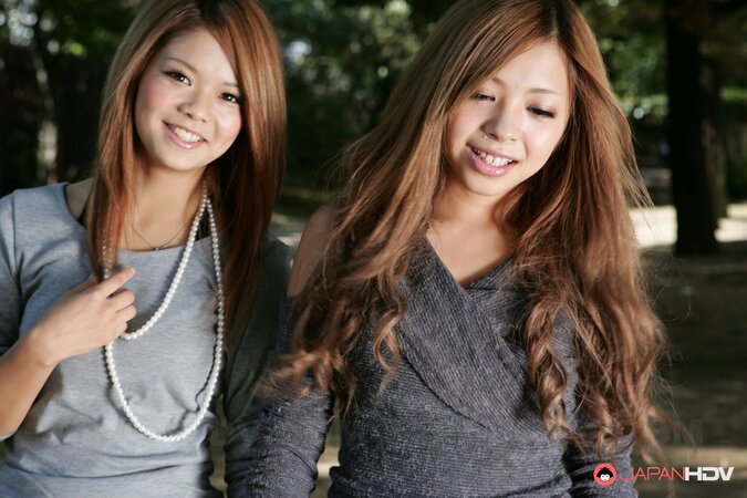 Excited Japanese girlfriends make out during promenade on city streets