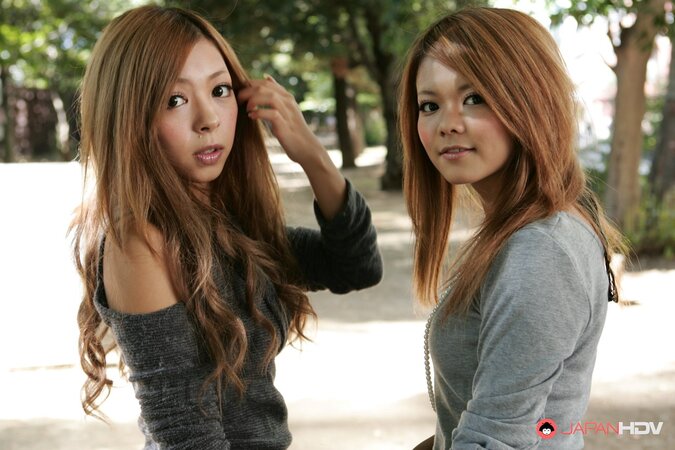 Excited Japanese girlfriends make out during promenade on city streets