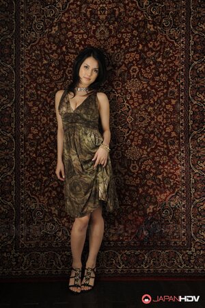 Brunette cutie in a sexy dress stands up against the carpet on the wall