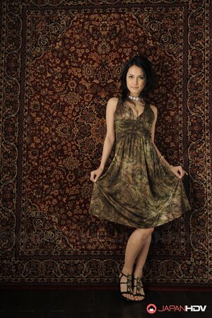 Brunette cutie in a sexy dress stands up against the carpet on the wall