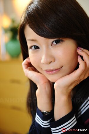 Skinny Eastern female in college uniform smiles so sweet and watches into camera