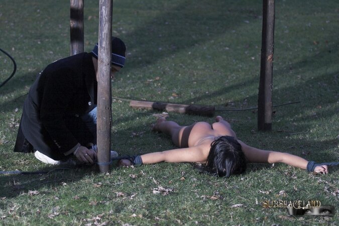 Master walks with dominated nude brunette on a leash and ties her up to the tree