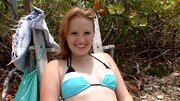 A smiling blue eyed honey is playing with a dick on the beach