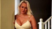A blonde milf places her hands on a large cock to tug it nicely